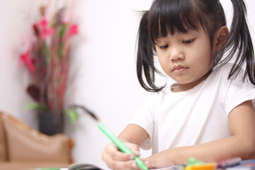 Happy smart cute adorable little Asian baby girl drawing on desk, educational creativity childhood