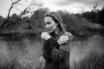 Girl model portrait near the river with hair. Pensive look. Beautiful eyes. Stylish clothes on the nature. Trees and plants.