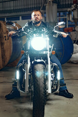 Obraz na płótnie Canvas Man motorcyclist sitting on his motorbike in underground parking