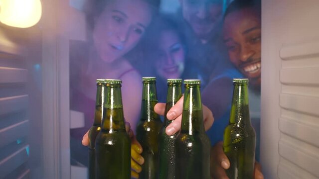 Group of young multiethnic friends sharing beer from fridge for home party