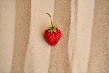 strawberries lie on the hot sand in the desert. Rays of the Sun. Top view. center orientation