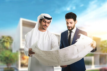 Pretty architect is explaining to Arab builders the plan of construction. The foreman pointing at...