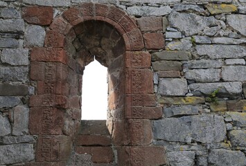 A decoratively carved arched window in a ruined church.