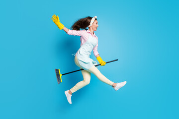 Full length body size view of her she nice attractive cheerful cheery glad girl housekeeper cleaner jumping riding broom like horse fooling isolated on bright vivid shine vibrant blue color background