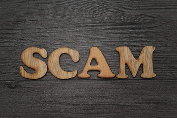 scam text word concept, wooden lettering alphabet over grunge background