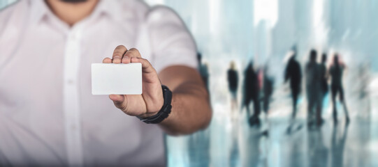 Man holding white business card in modern office background.