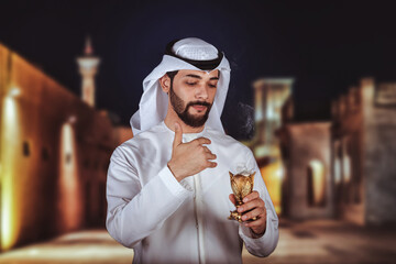 Arab man holding Bakhour holder celebrating the holy month of Ramadan Kareem standing front old...