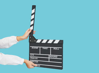 Child hands with cinema clapperboard on blue color background.