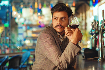 young man drinking wine in bar