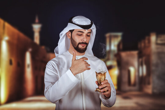Arab man holding Bakhour holder celebrating the holy month of Ramadan Kareem standing front old city in Dubai.