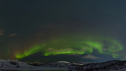 Northern lights over tundra and rocks.