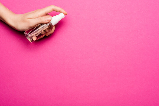 Partial View Of Woman Spraying Hand Antiseptic On Pink