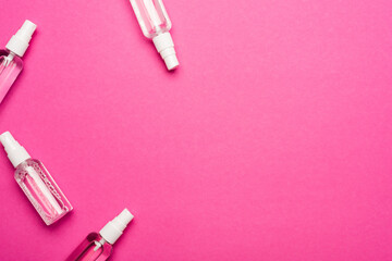 top view of transparent spray bottles with liquid sanitizer on pink