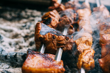 Skewers of pork ribs on a skewer in smoke. Cooking meat in nature..