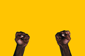 Powerful black fists raised calling for freedom and equality on a yellow background.