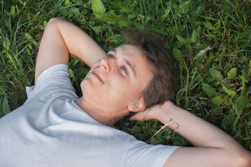 a young rural Slavic guy is lying on the grass