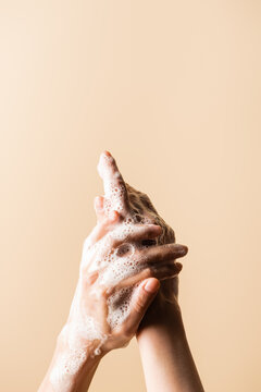 partial view of woman washing hands with soap foam isolated on beige