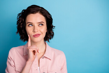 Closeup photo of attractive pretty interested lady short black hairdo look side empty space wondered arm on cheek wear casual pink denim jacket isolated blue color background