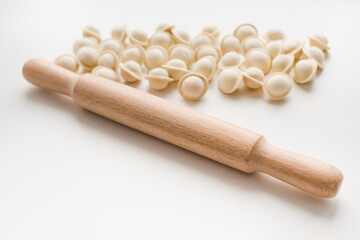 dumplings on white background, rolling pin for dough, semi-finished products