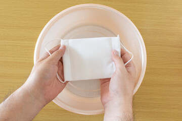 布マスクを水で手洗いする男性の手元