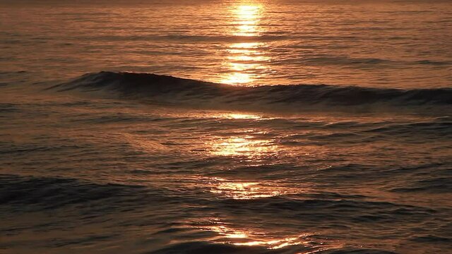 Detalle de mar al amanecer con tonos dorados de reflejos del sol en el agua y las olas