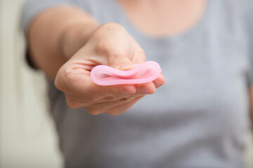 Close up of woman hand folding menstrual cup showing how to use. Women health concept, zero waste alternatives