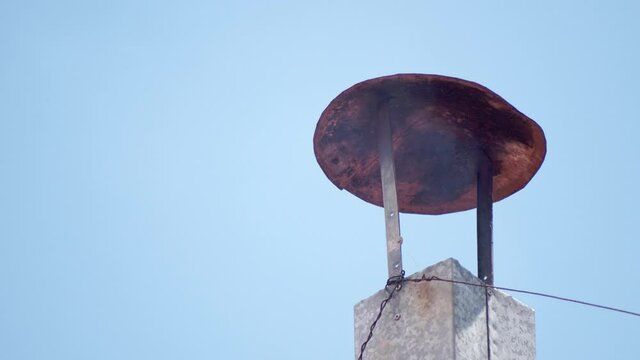 Close up of smoke coming out of a rusty chimney in a bright day with a clear sky in the background.