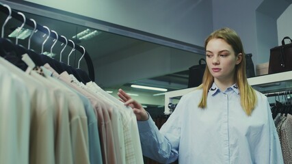 Young pretty girl in boutique selecting clothes to buy.