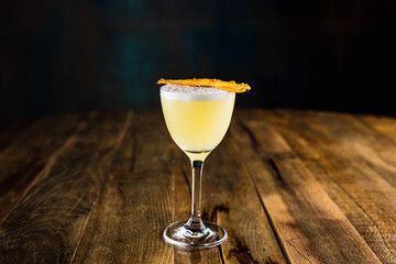 A pineapple sour cocktail in a nick and nora glass