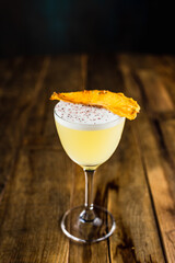 A pineapple sour cocktail in a nick and nora glass