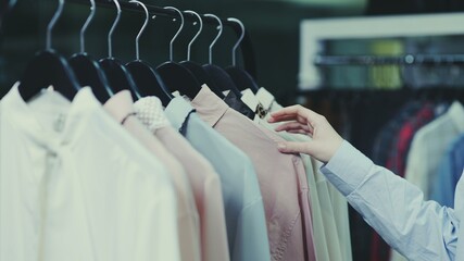 Unrecognasible woman toutch clothes on hangers in shop
