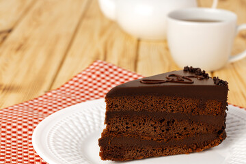 Piece of chocolate cake on white plate on table