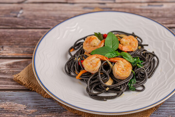 Black Spaghetti with spicy fried shrimp on a wooden table