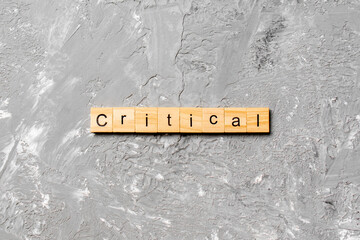 critical word written on wood block. critical text on table, concept