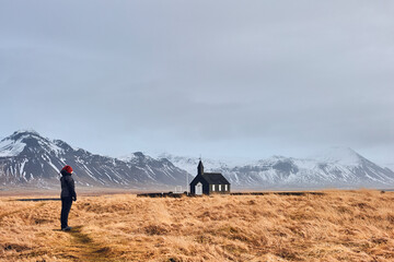 Northen landscapes: Woman contemplating the loneliness of the Budir Church in the Icelandic...