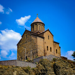 Fototapeta na wymiar It's Metekhi Church on the elevated cliff that overlooks the Mtkvari river, one of the most popular landmarks of Tbilisi