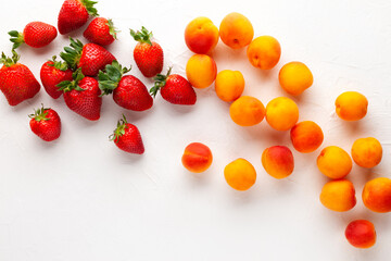 Fresh organic apricots and strawberry on white background. Vegetarian, clean and healthy eating concept. Flat lay, copy space.