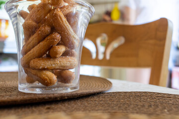 A transparent cup of savojardi cookies stands on a napkin against the background of a wooden chair. High quality photo