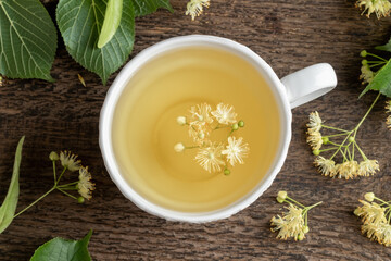 A cup of linden tea with linden flowers on a table