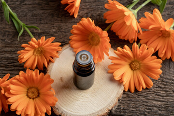 A dark bottle of essential oil with calendula flowers