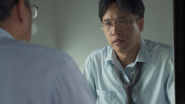 4K Unemployed Asian businessman standing in front of the mirror screaming and blame himself of mistake. Stressed man entrepreneur unsuccessful in business. Mental health and economic problem concept.