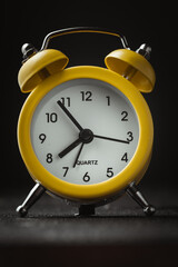 Yellow vintage alarm clock on the black background. shallow depth of field