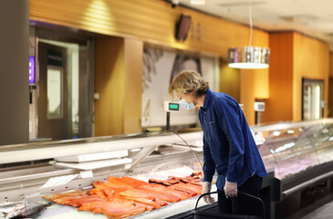 Supermarket shopping, face mask and gloves,man shopping for fresh fish seafood in supermarket retail store.