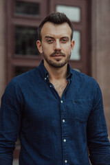 Portrait of young man standing near building.