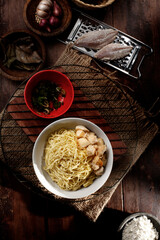 Chicken noodle. A bowl of boiled noodles seen from above, topped with seasoning broth and a sprinkling of pieces of chicken.