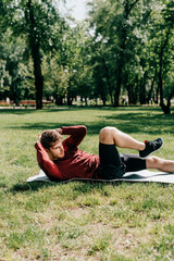 Side view of sportsman doing abs while working out on fitness mat in park