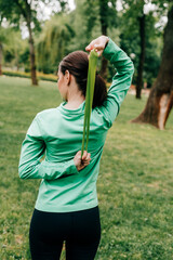 Back view of sportswoman exercising with resistance band in park