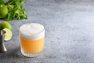 Pisco sour cocktail of wiskey with lime, egg white, honey on grey. Close up. Space for text.