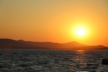 zachód słońca na tle morza i gór