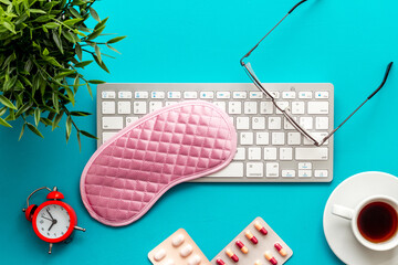 fatigue concept. Sleep mask on blue office desk from above